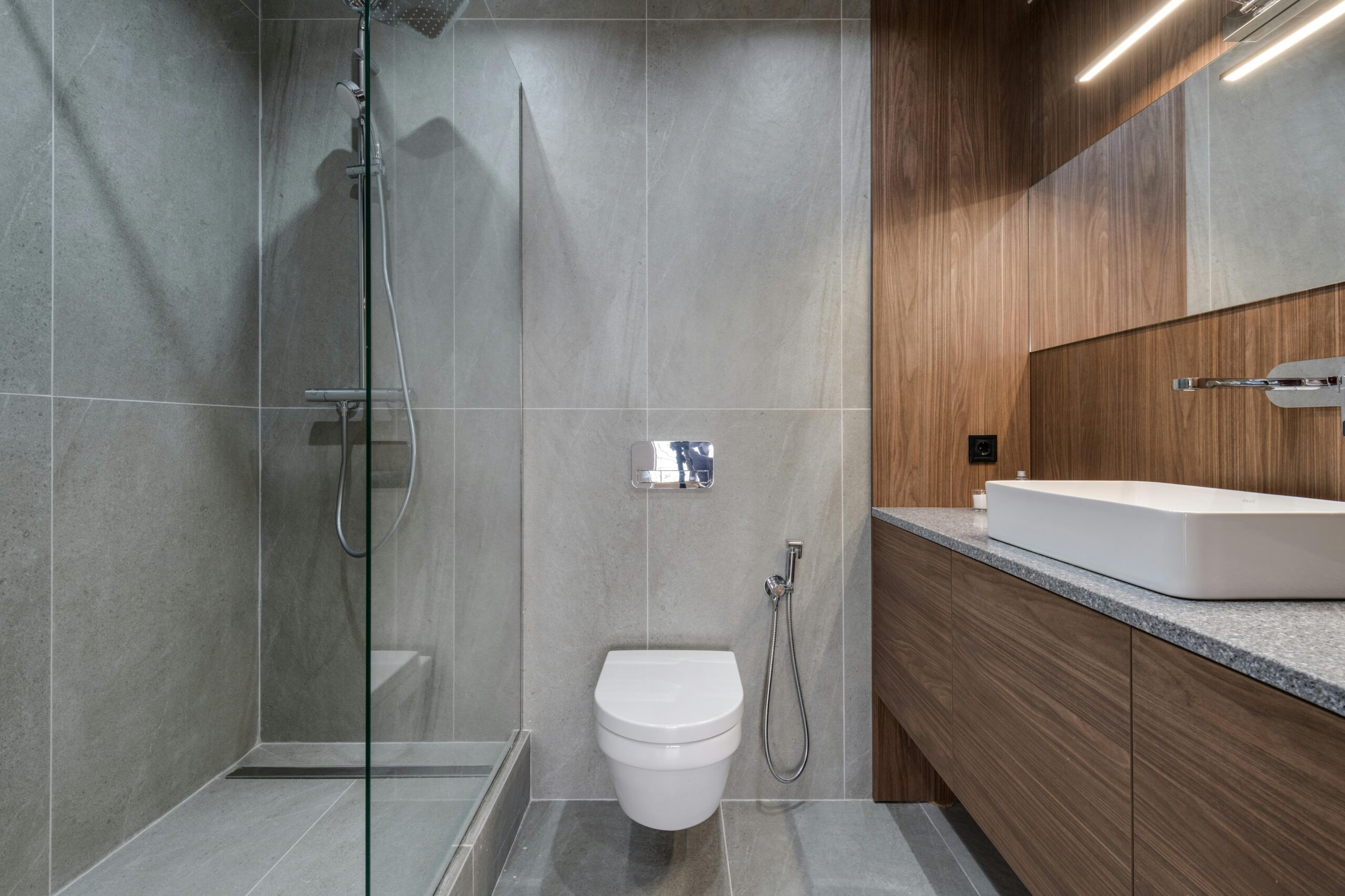 Projects Elegant modern bathroom featuring a walk-in shower, sink, and toilet with a stylish wooden finish.